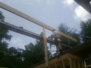 Carpenter setting a ridge beam over a new addition frame — Ice Dam Removal by Roofing Brothers in Merrick
