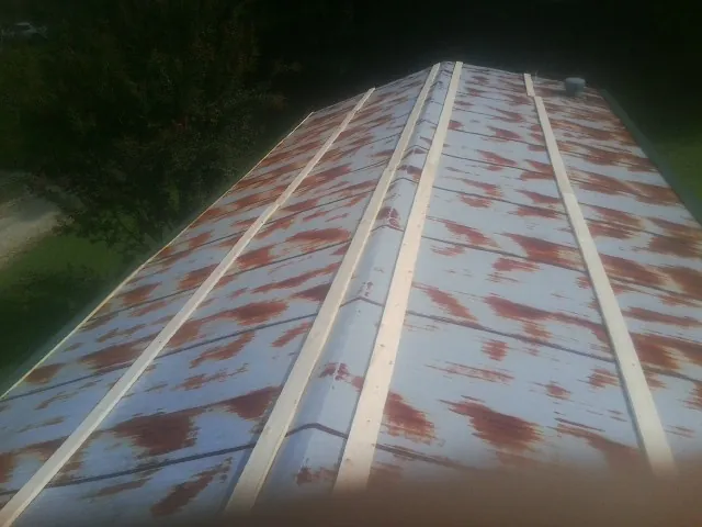 Rusted metal roof panels with new wood purlins before replacement — Storm Damage Roof Repair in Merrick by Roofing Brothers