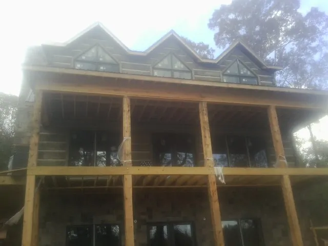 Dormers and porch framing on a large log home under construction — Roof Coating work by our crew in Merrick