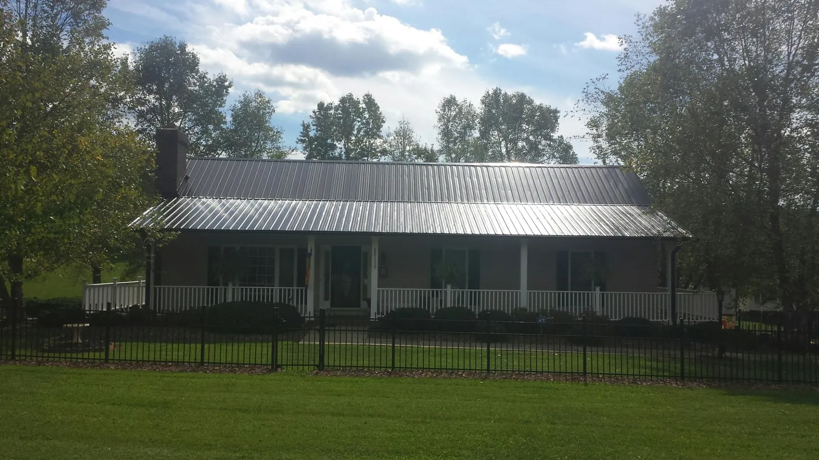 Gray metal roof on a brick ranch with a full width front porch — Gutter Guard Installation work by our crew in Merrick