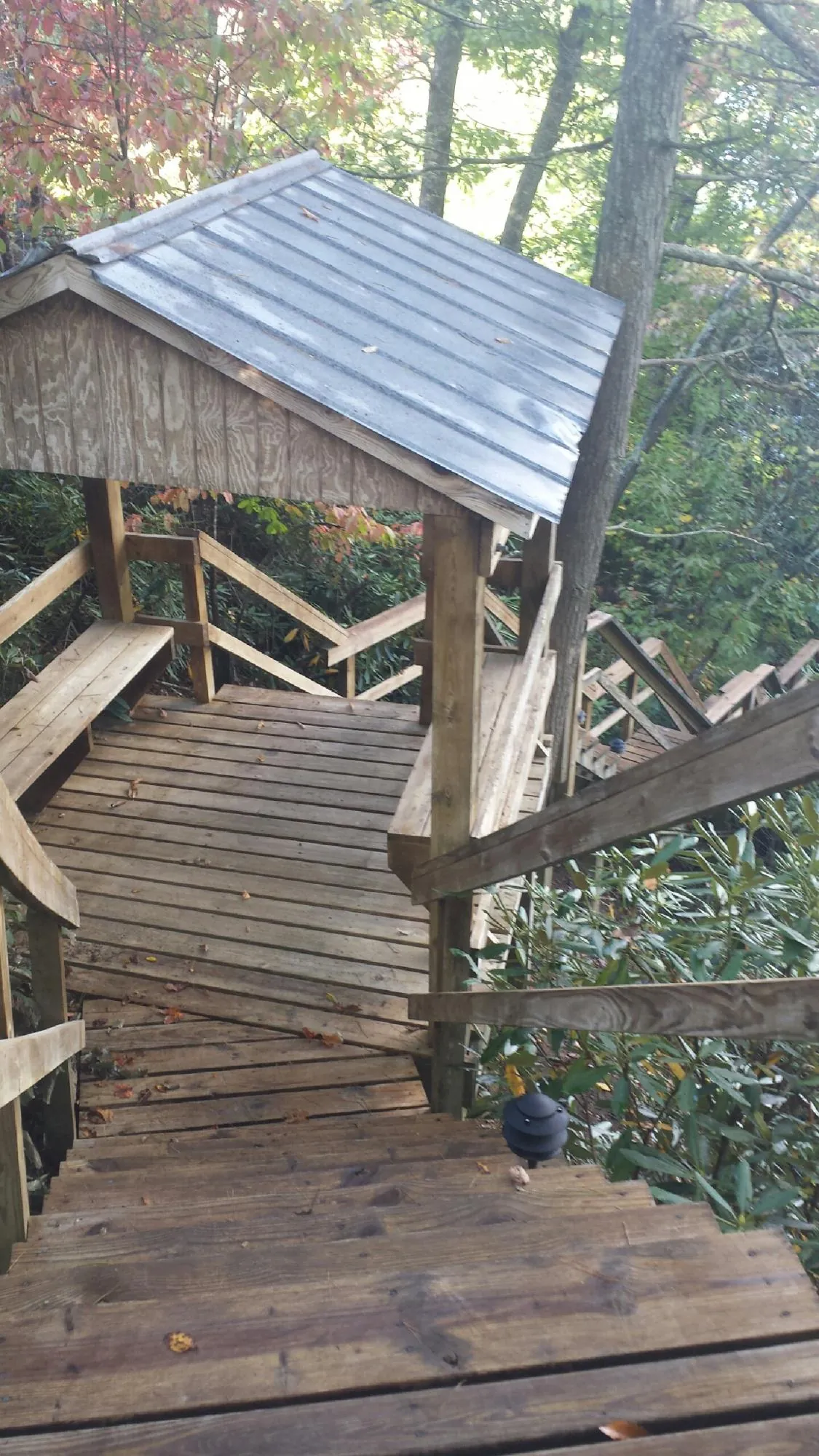 Metal roofed shelter over wooden steps on a wooded walkway — Skylight Repair & Installation work by our crew in Merrick